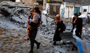 Palestinians carry their belongings as they walk on a debris-strewn street in the aftermath of Israeli strikes at Beach refugee camp in Gaza City. Over 10,000 Palestinians have been killed in Gaza following the Hamas surprise attack in Israel on October 7, 2023. 
